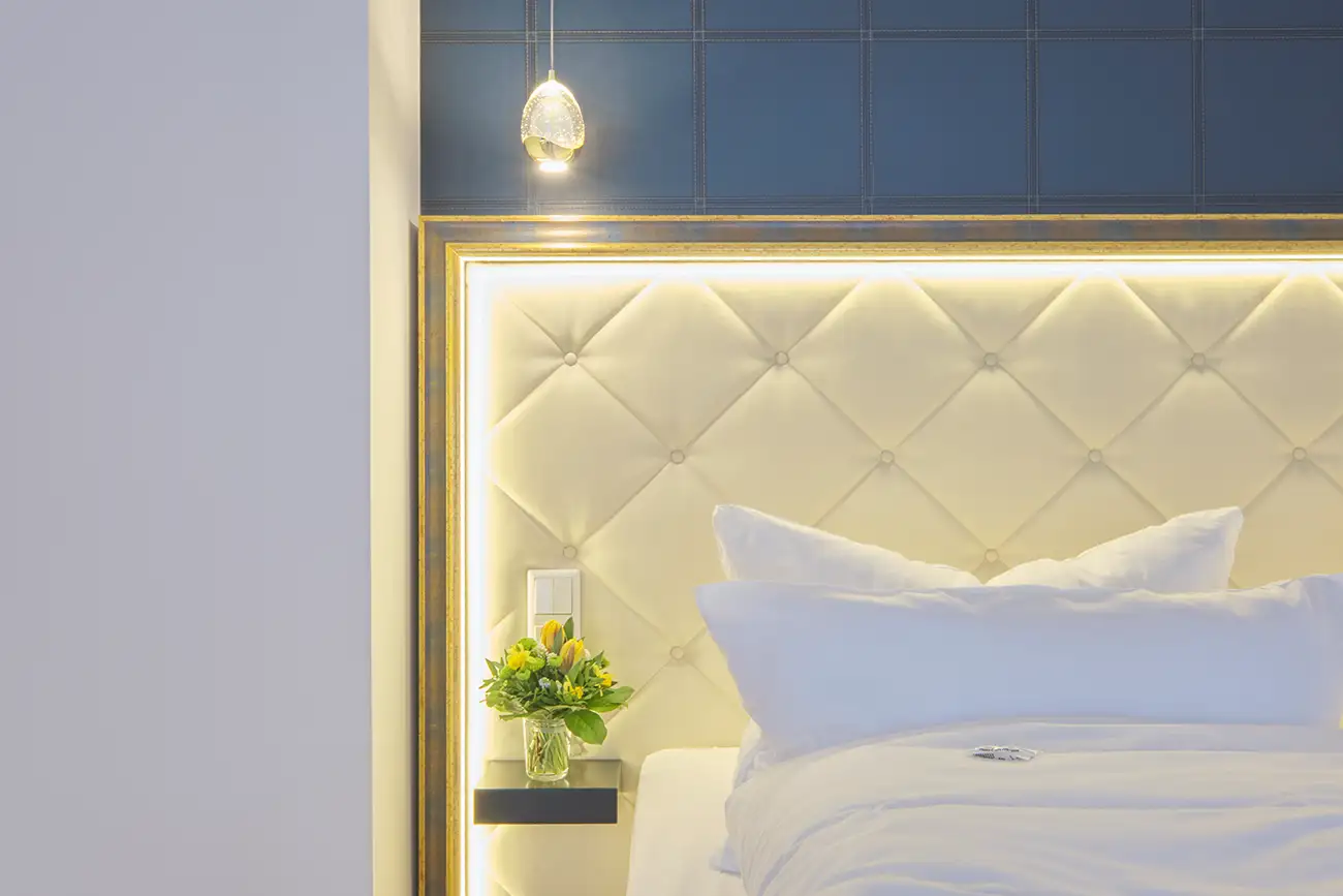 Hotelbett mit beleuchtetem Kopfteil und frischer Bettwäsche